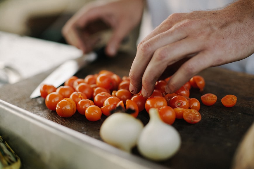 Person chopping tomatoes and garlic